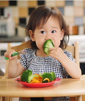Enfant mangeant un brocoli