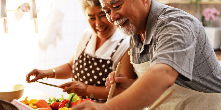 Couple de personnes âgées d'origine asiatique cuisinant des légumes - Equation nutrition - Aprifel